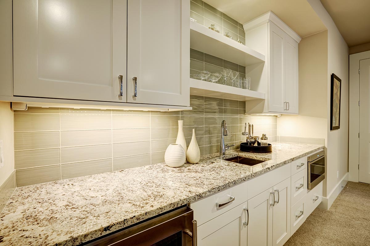 Granite countertop finished with a glass tile backsplash