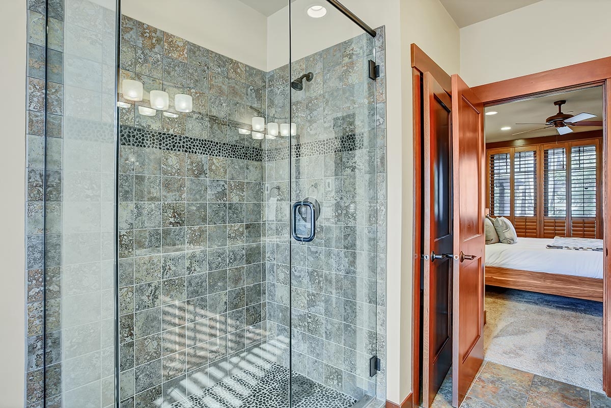 Grey tiled walk-in shower with glass panel